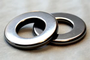 A pair of stainless steel washers on a white surface.