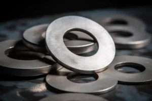 A pile of metal washers, including flat washers and hex bolt washers, on a table.